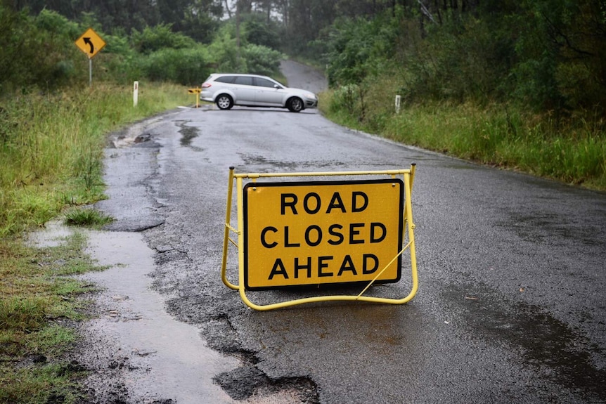 A road closed sign near a car