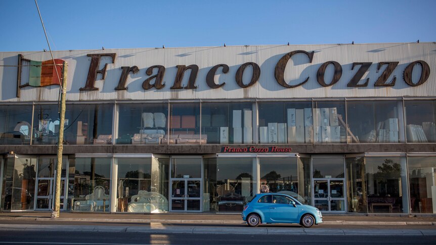 A car drives past Franco Cozzo furniture store.