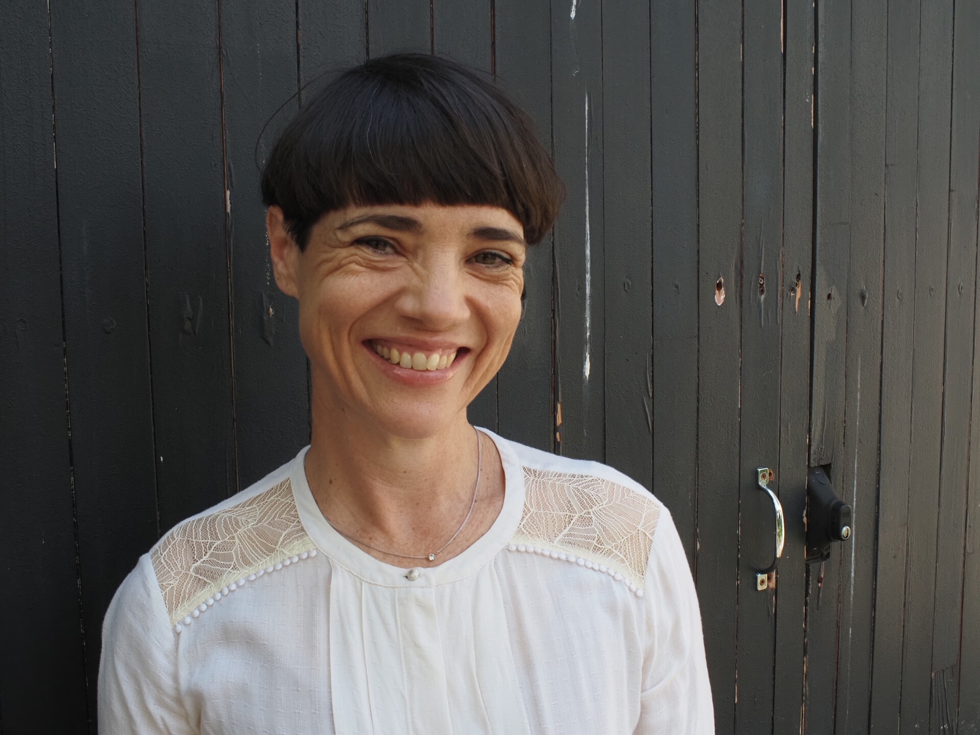Woman with short bob and white shirt smiling at the camera