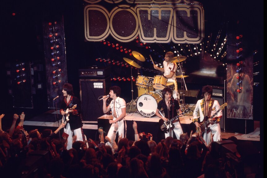 Bay City Rollers on stage in TV studio as audience wave hands.