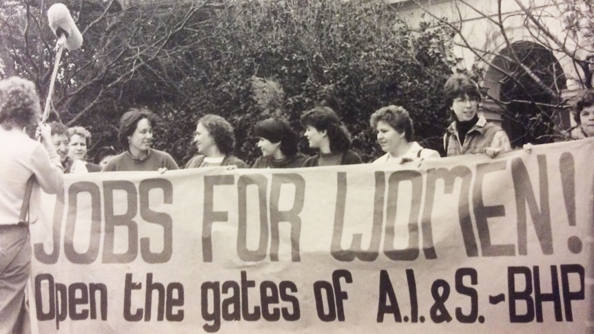 Women hold a banner that reads 'Jobs for Women! Open the gates of A.I.&S - BHP.