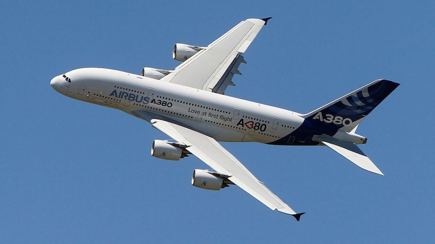 Airbus A380 flies through a clear blue sky.