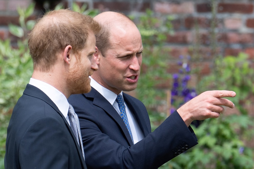 Il principe William e Harry parlano tra loro.