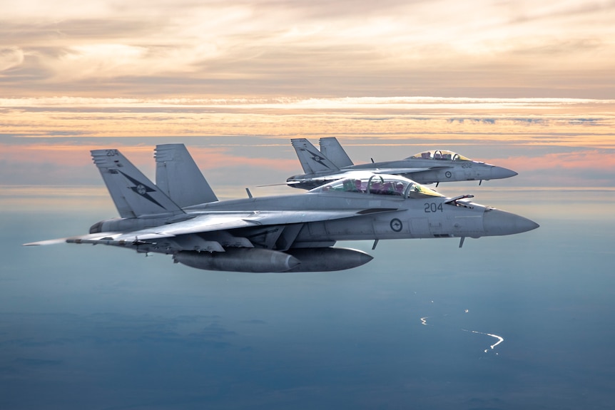 Two Australian fighter jets fly during sunset