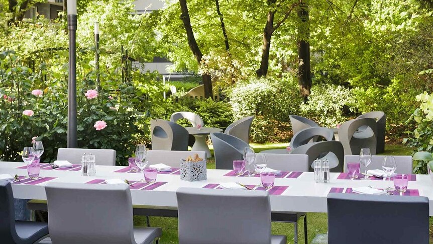 A table set in a sunlit, lush Mercure Paris Centre hotel