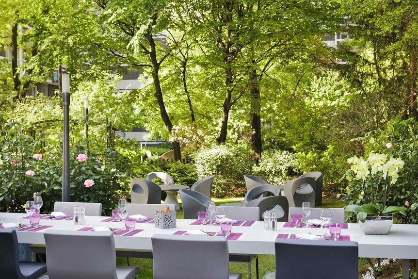 A table set in a sunlit, lush Mercure Paris Centre hotel