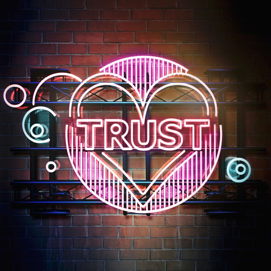 pink neon sign reading trust with a heart around it