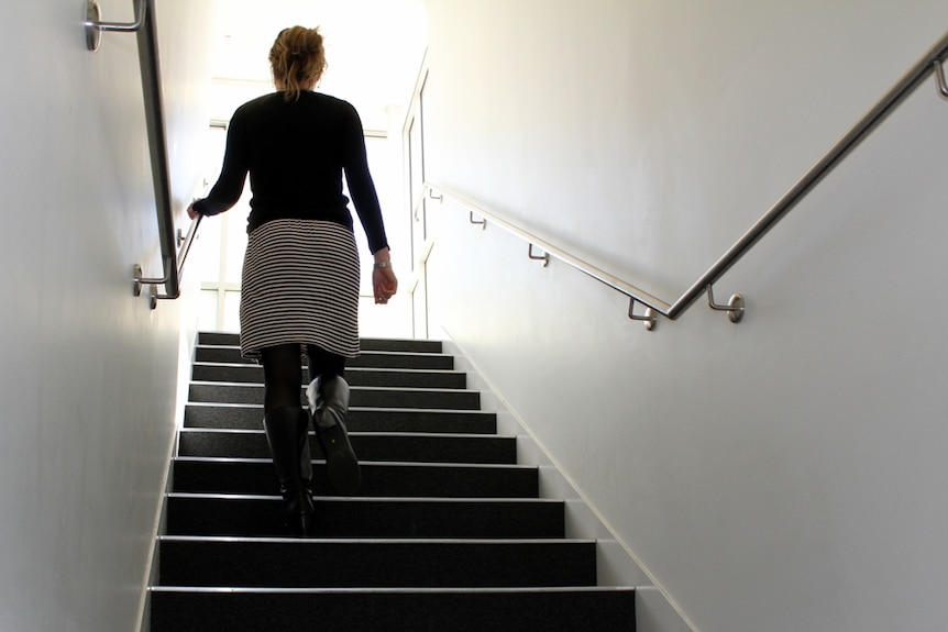 An officer worker walking up stairs.