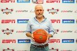 Man holding basketball in front of sponsorships 