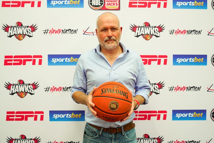 Man holding basketball in front of sponsorships 