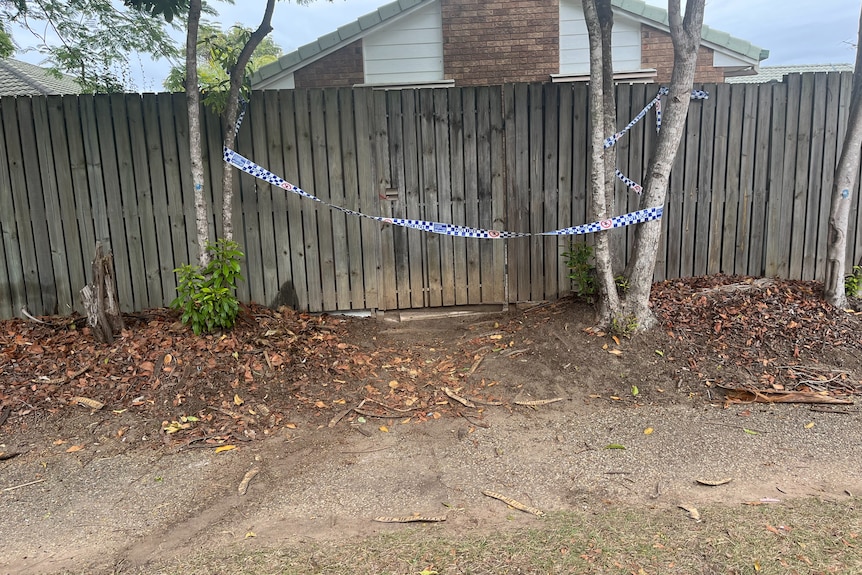 Police tape across a fence and gate.