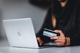 Generic image of a person shopping on computer with credit card in hand