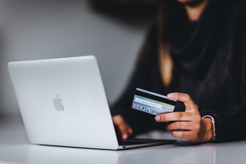 Generic image of a person shopping on computer with credit card in hand