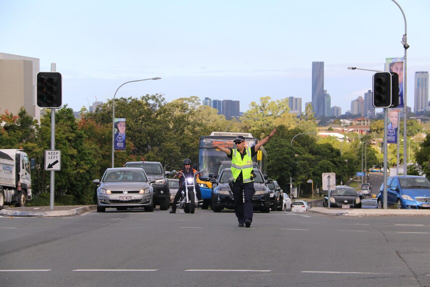 A police officer stands in the centre of an intersection guiding traffic.