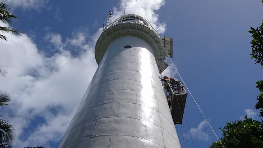 photo looking up at the lighthouse with painter hanging off side