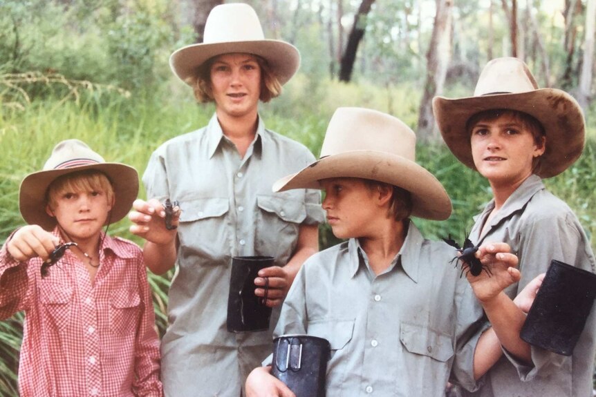 Four children wearing felt cowboy hats and khaki shirts hold quart pots and yabbies in bushland