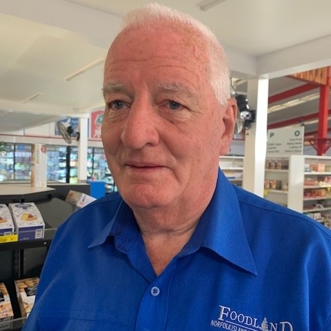 A man wearing a blue shirt with grey hair smiles for the camera 