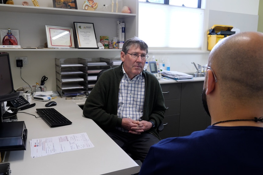 A doctor in a  surgery speaks to a colleague in his surgery