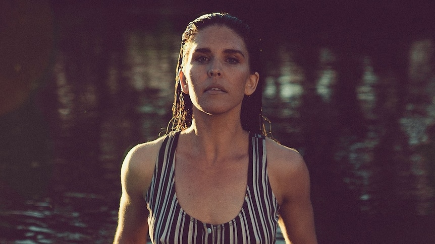 Fanny Lumsden emerges from a waterhole wearing a bathing suit with slicked back wet hair