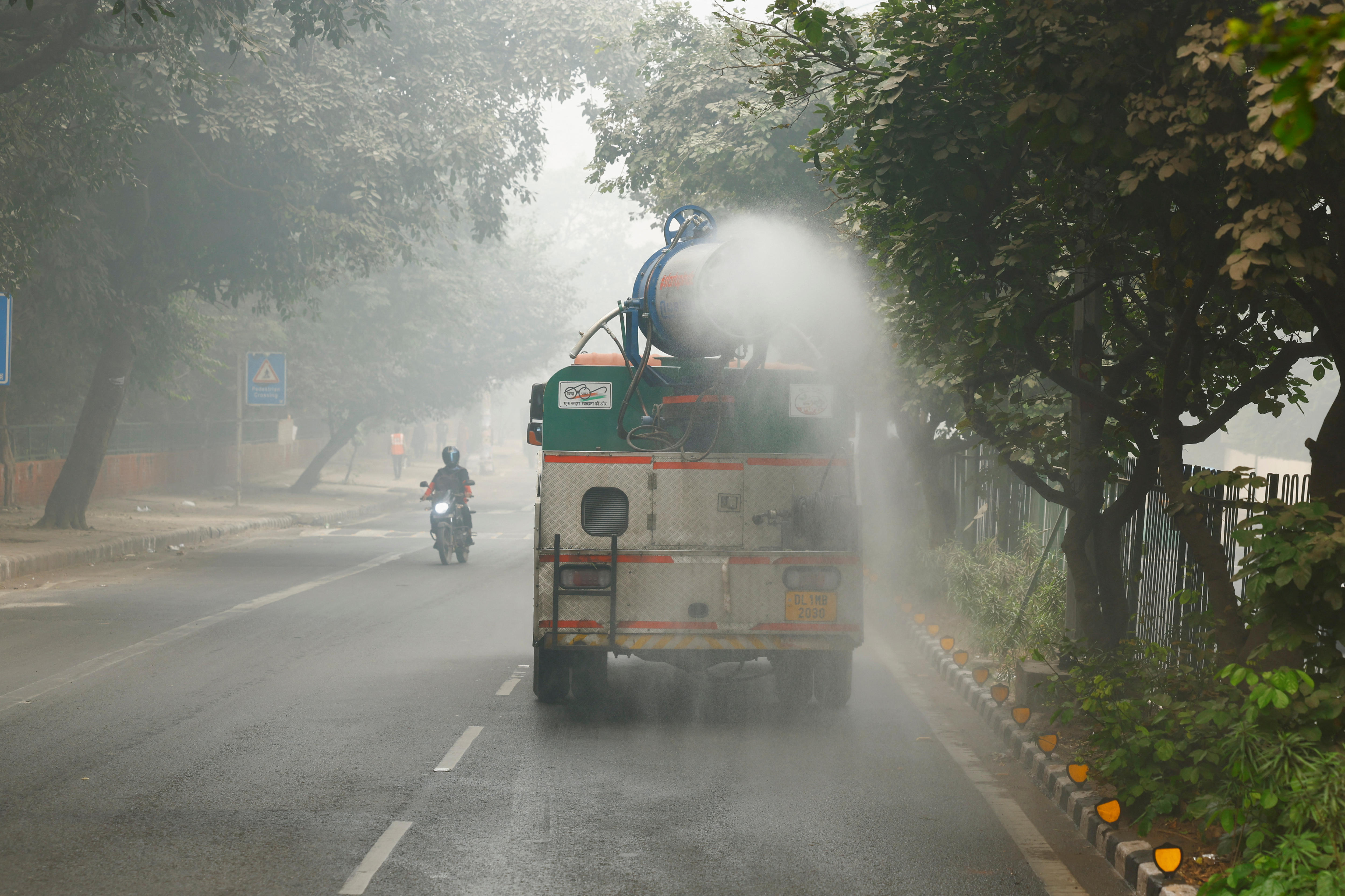 A vehicle sprays water on the road to curb dust and pollution