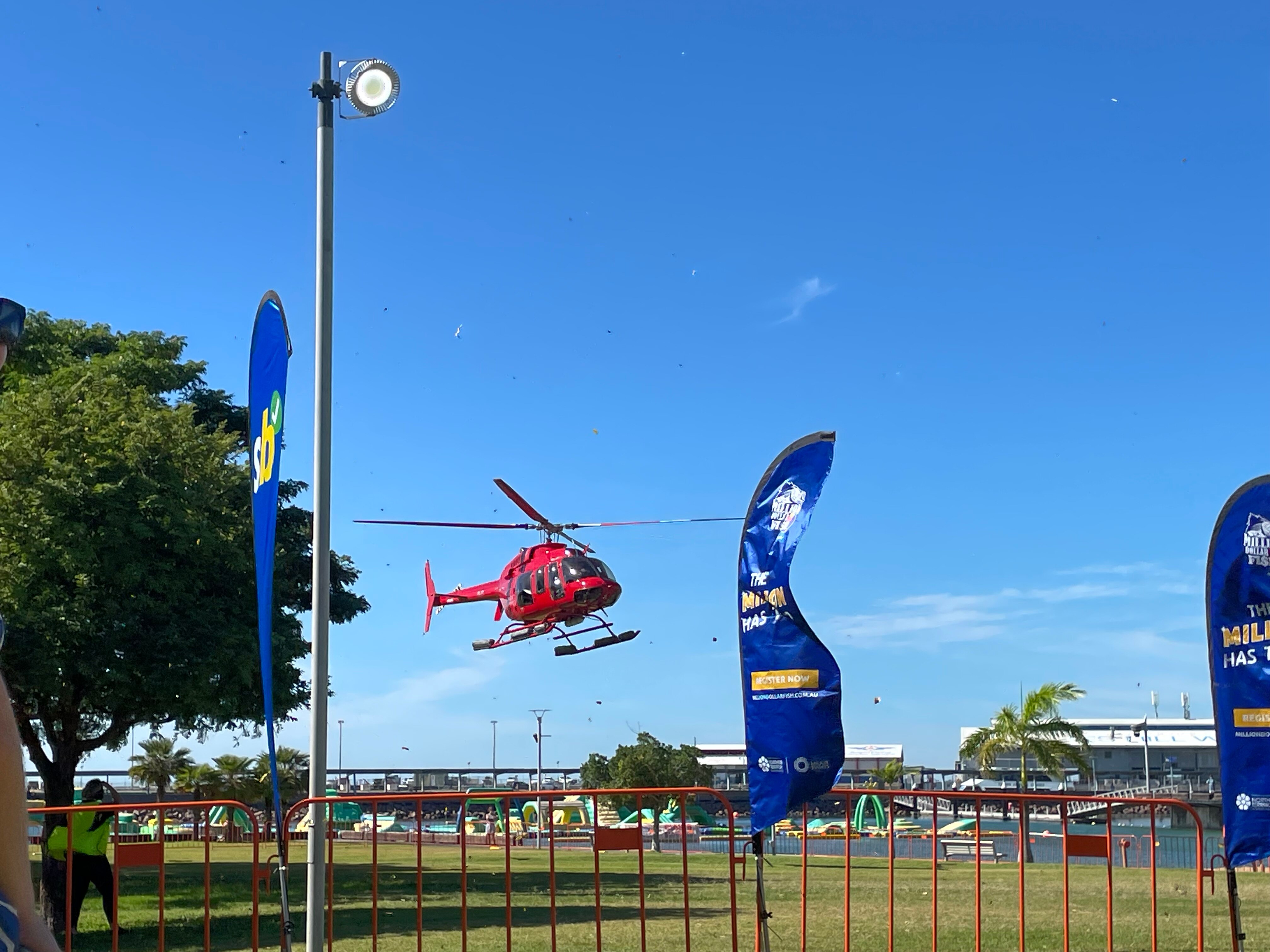 A helicopter landing in a waterfront park with blue sunny skies.