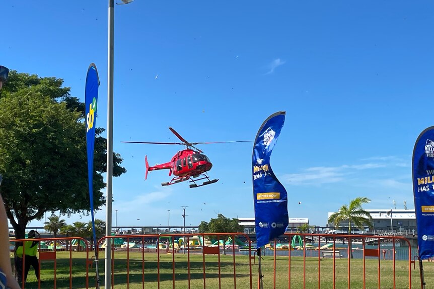 A helicopter landing in a waterfront park with blue sunny skies.