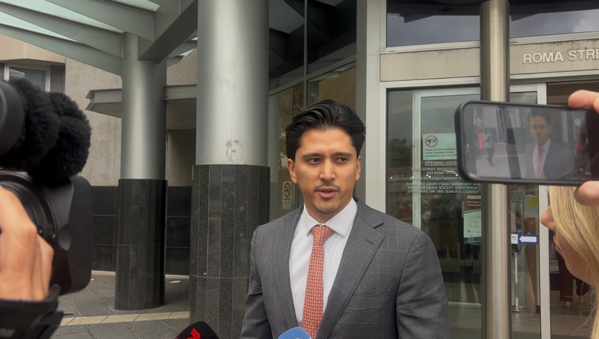 A man in a suit with dark hair standing outside Brisbane court