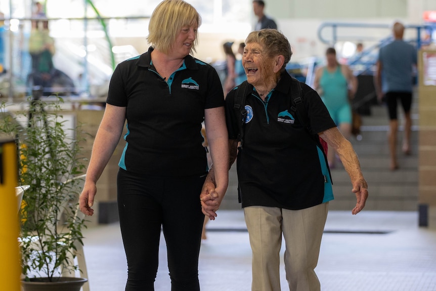 wo women, one elderly, walk next to a pool