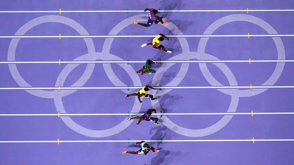 An aerial photo of athletes running over the Olympic rings
