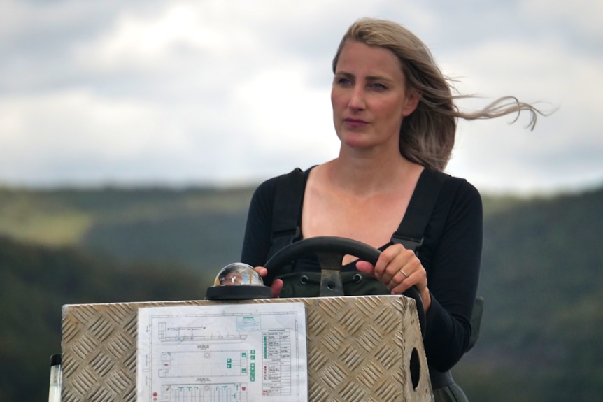 Woman drives boat looking ahead with a straight face