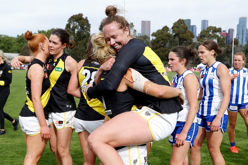 Two Richmond Tigers players embrace while others shake hands behind them.