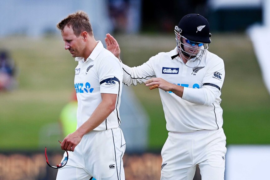 A New Zealand Test cricketer pats his injured teammate on the back as he leaves the ground in pain.