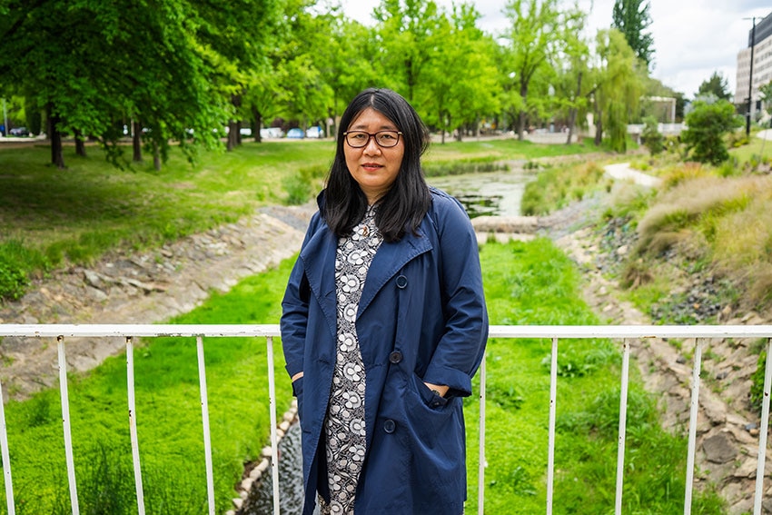 A woman standing in front of a railing in a park