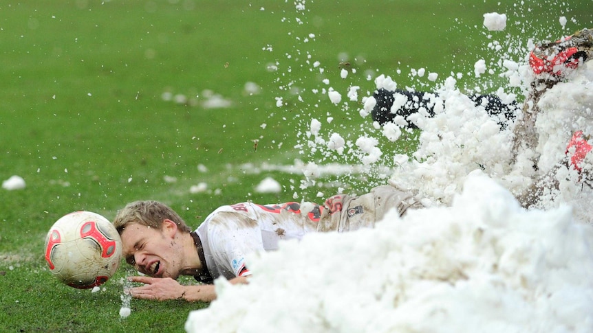 Christopher Buchtmann slides into a heap of snow during a 2nd division Bundesliga match.