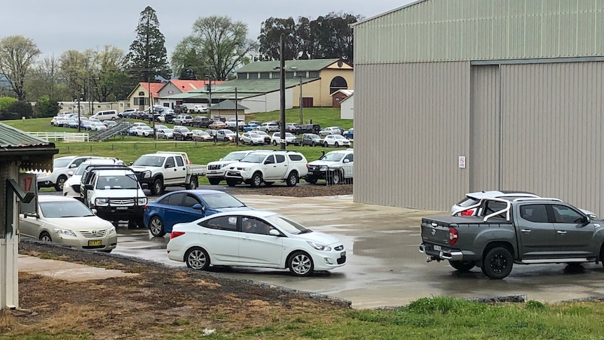 Cars queued up outside a large shed 