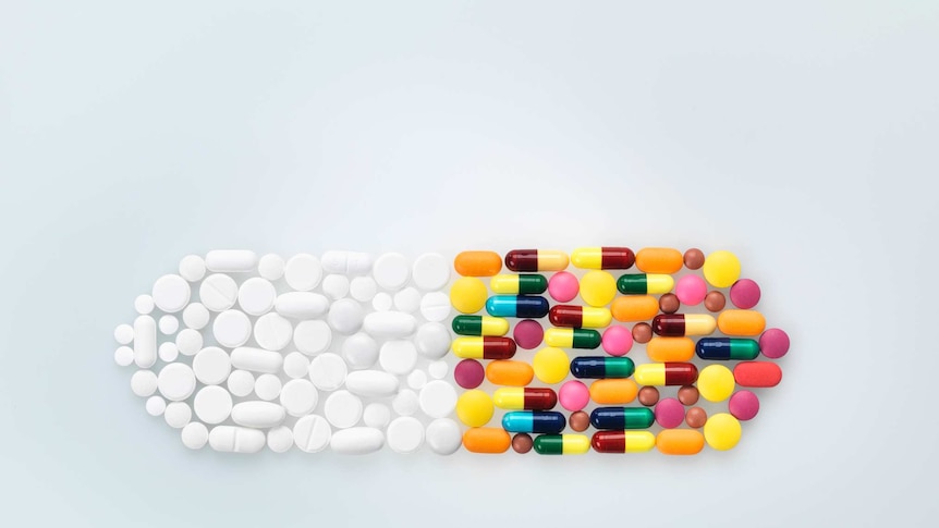 White and coloured pills assembled into the shape of a pill