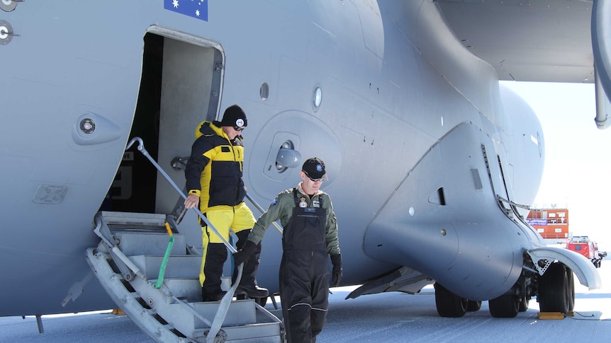 Two men disembarking from RAAF cargo plane.