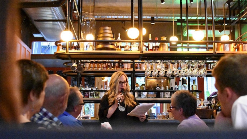 Hilary Bonney stands by the bar at the Garden State Hotel, speaking about telling legal stories.