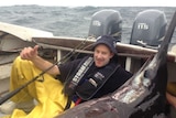 Tasmanian fisherman Leo Miller lies in a boat next to a broadbill swordfish.