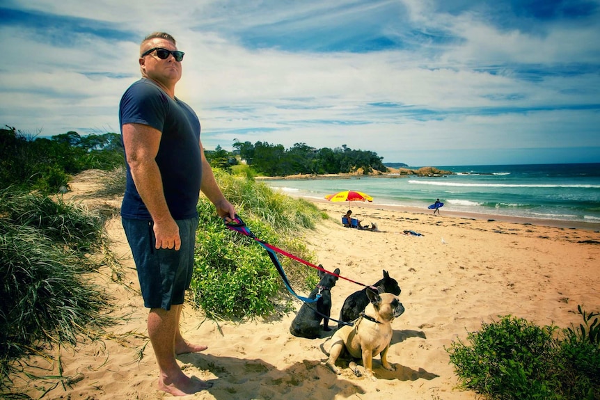 Patrick O'Conner on the beach with his three dogs on leads