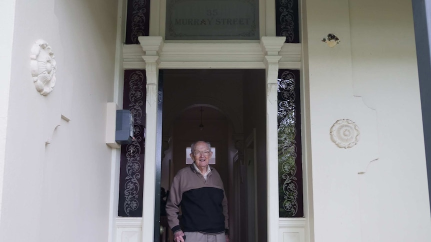 Stan McKay stands in the doorway under a sign that says '35 Murray St'