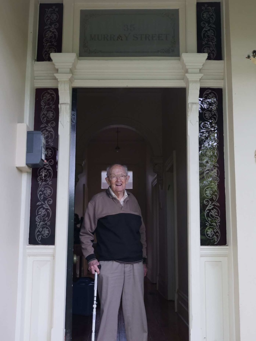 Stan McKay stands in the doorway under a sign that says '35 Murray St'