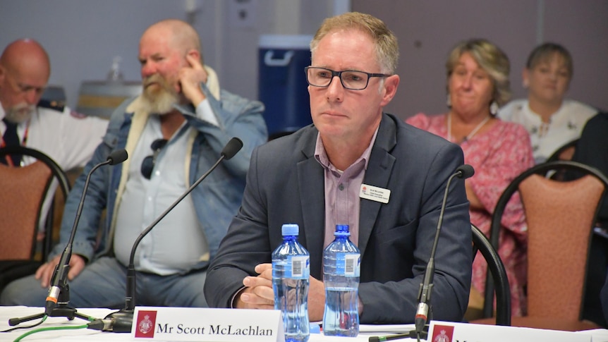 Man sitting at table giving evidence at inquiry