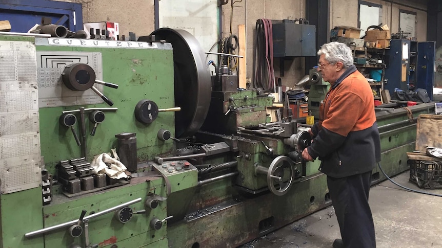 A man uses a large manufacturing machine.