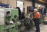 A man uses a large manufacturing machine.