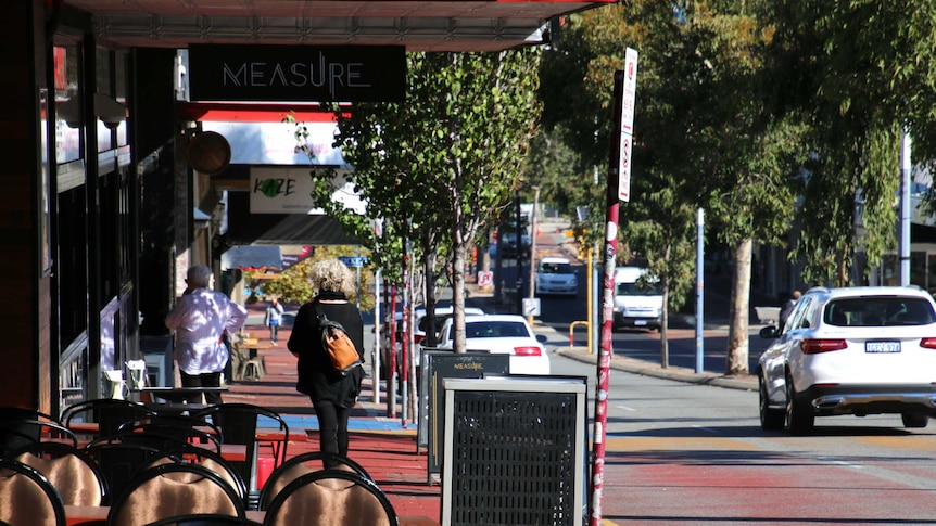 A section of Beaufort Street with chairs outside a restaurant and trees lining the median strip.