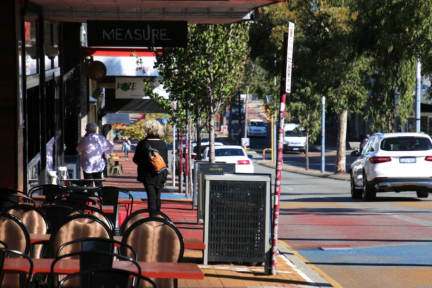 A section of Beaufort Street with chairs outside a restaurant and trees lining the median strip.