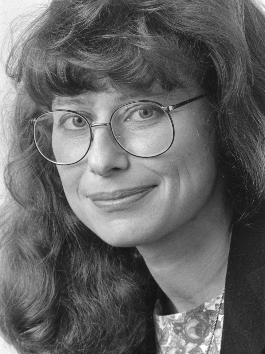 Black and white portrait shot of Kohn wearing round glasses with long wavy hair.