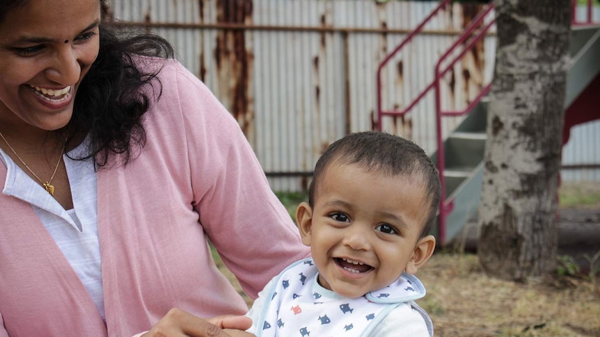 Nandini Nair smiles while looking at her son son Dev in a Mount Isa playground.