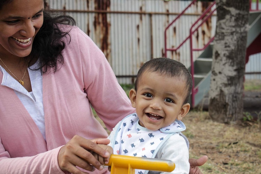 Nandini Nair smiles while looking at her son son Dev in a Mount Isa playground.